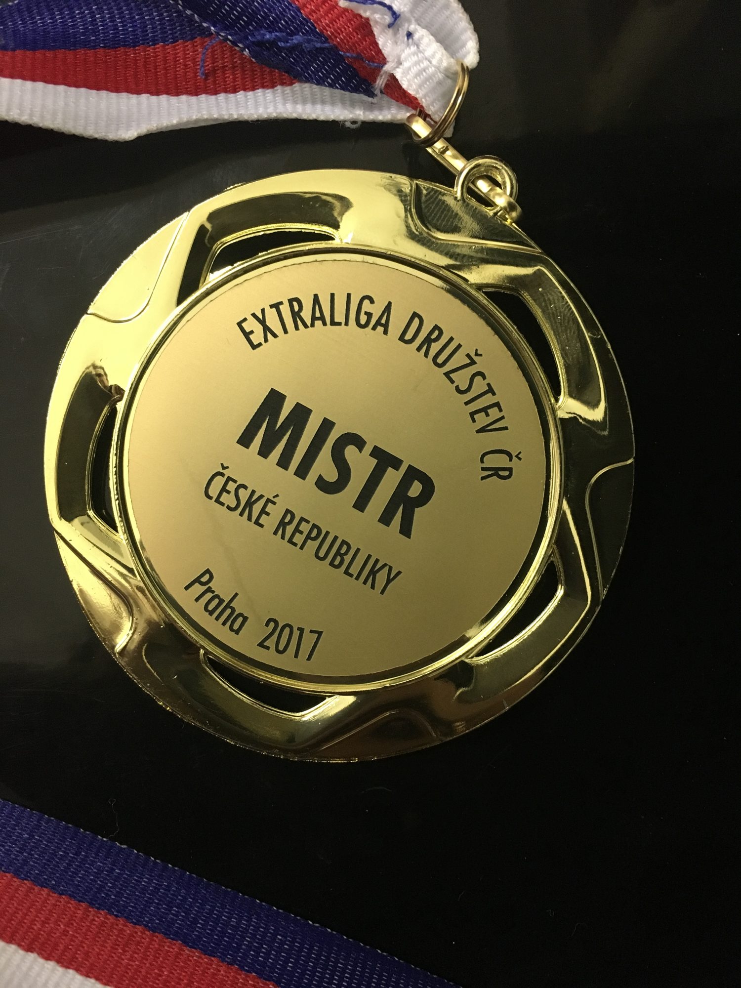 Zlatá medaile s&nbsp;nápisem Extraliga družstev ČR, Mistr České republiky, Praha 2017, na trikolóře