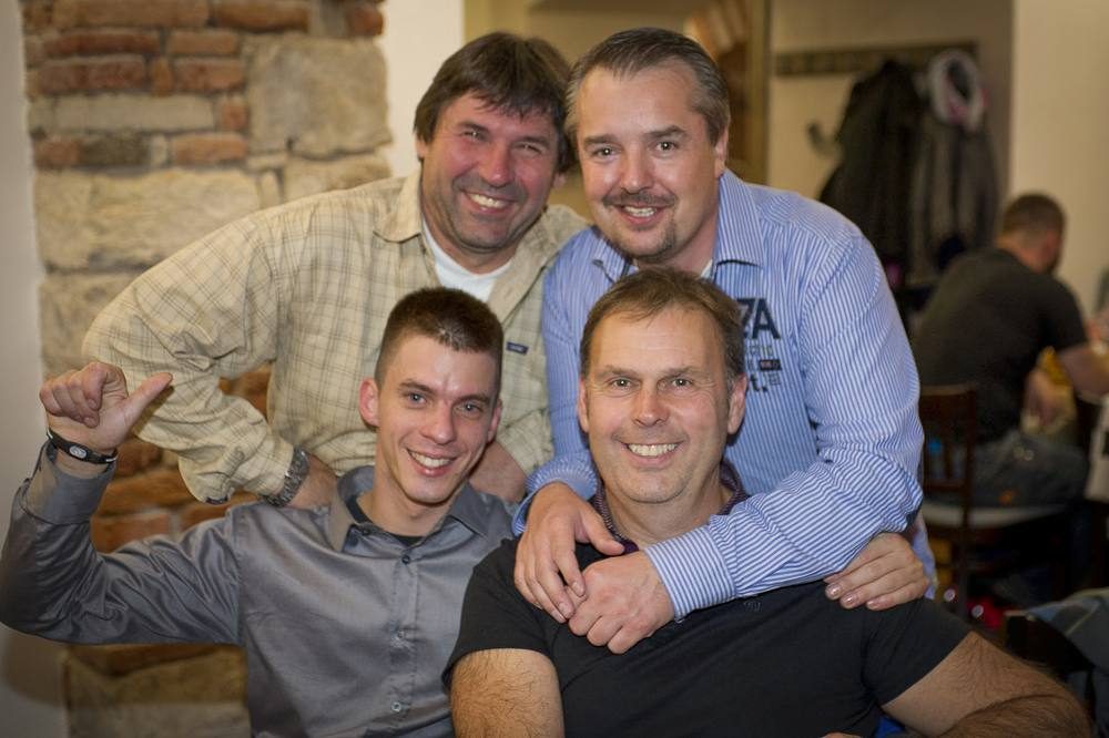 Čtyři muži se usmívají při společné fotografii v&nbsp;restauraci